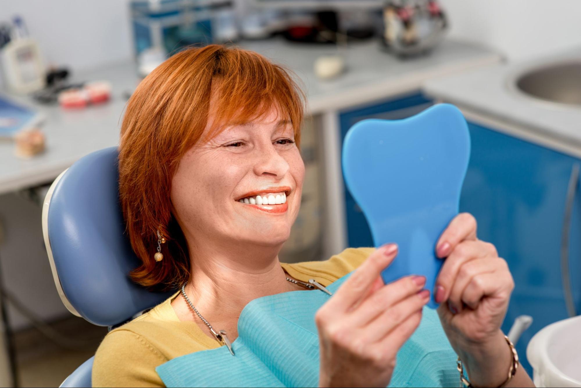image9 Older female patient looking at teeth in the mirror.